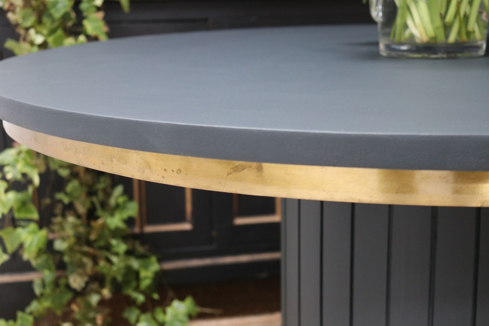 photo furniture Stunning Black Round Dining Table With Brass Metal Edge Slatted Wood Column Base