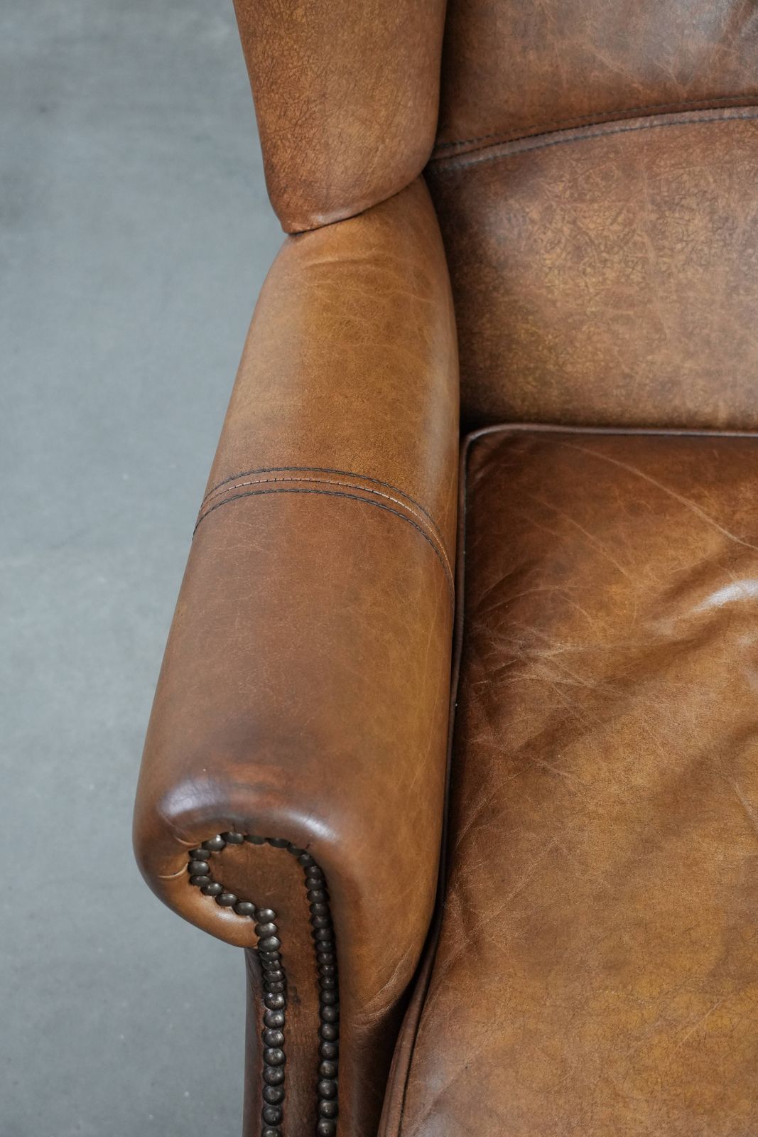 Tijdloze Cognackleurige Oorfauteuil In Engelse Stijl, Bekleed Met Koeienleer En Afgewerkt Met Decoratieve Sierspijkers En Fraaie Details. photo buy