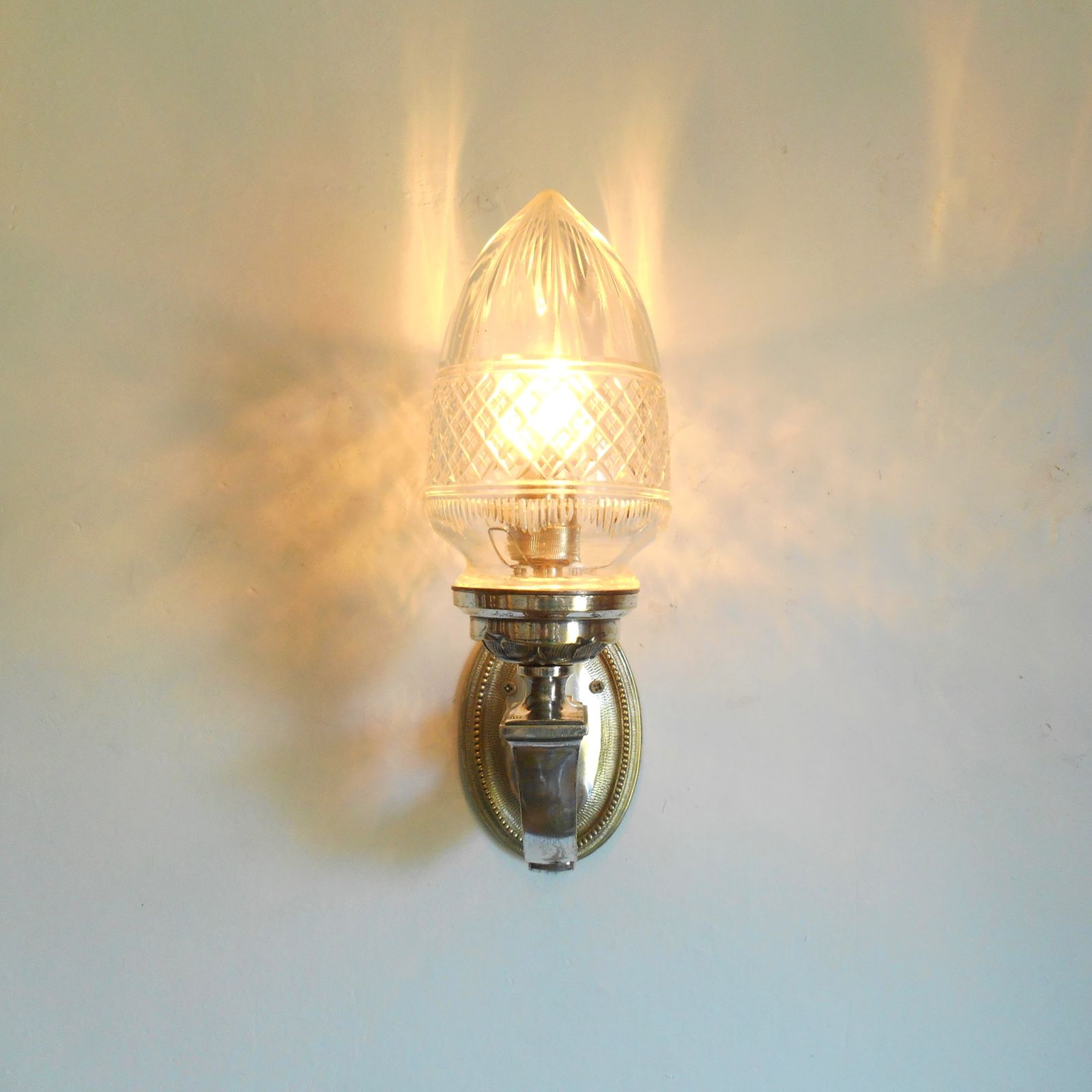 Antieke vernikkelde wandlamp met een geslepen glazen eikelvorming kap photo Verlichting