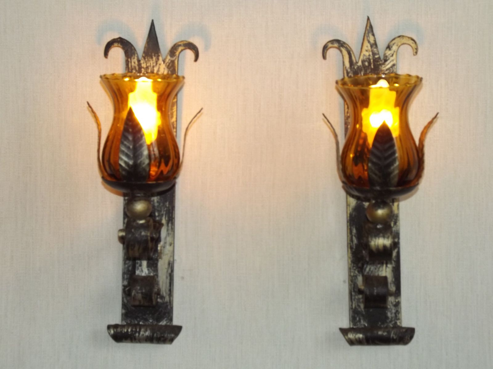 Paar handgesmede smeedijzeren wandlampen in middeleeuwse stijl met amberkleurige glazen kappen photo Verlichting