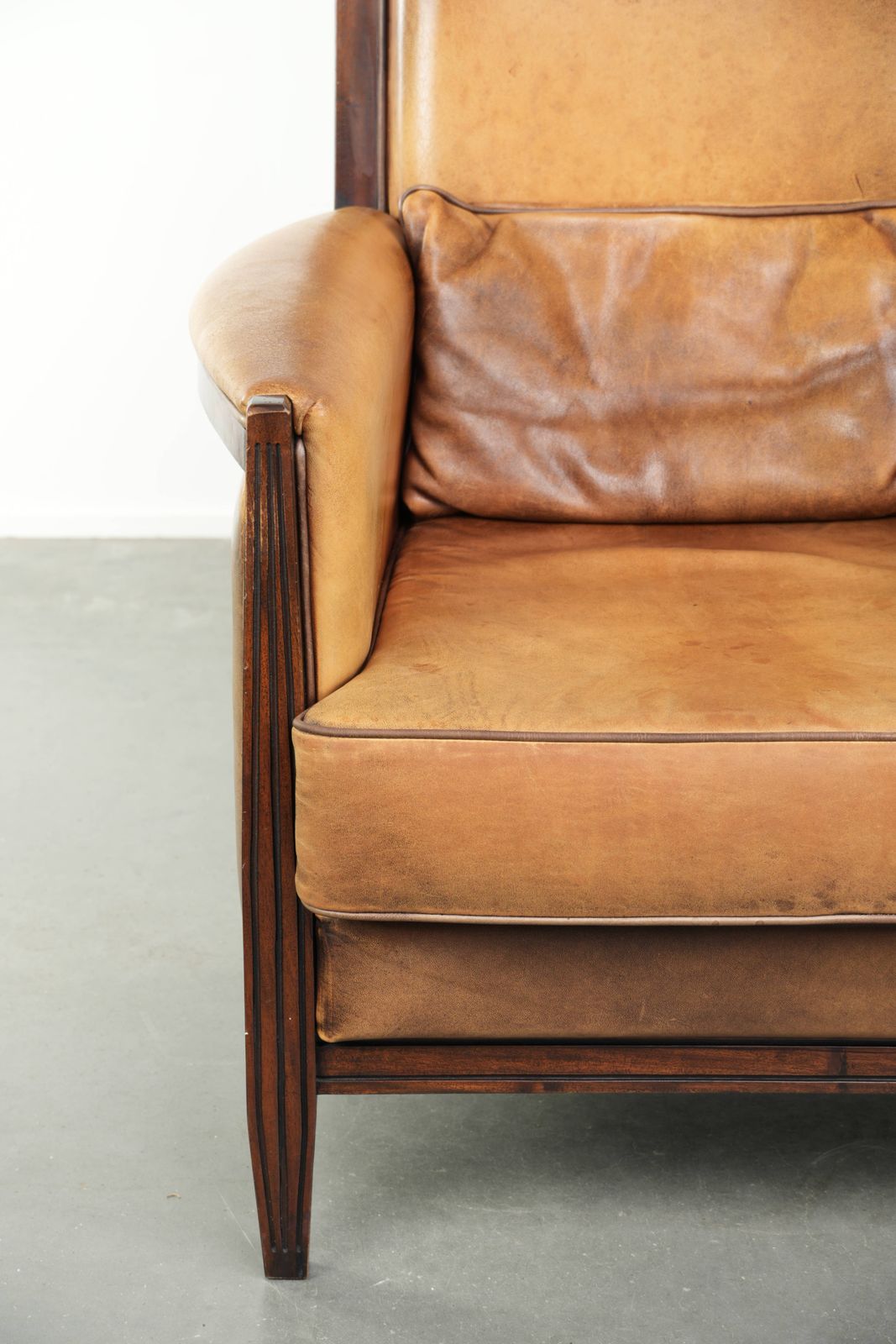 photo furniture Comfortable Cognac Colored Art Deco Design Armchair Made Of Sheepskin Combined With Wood, With A High Back.