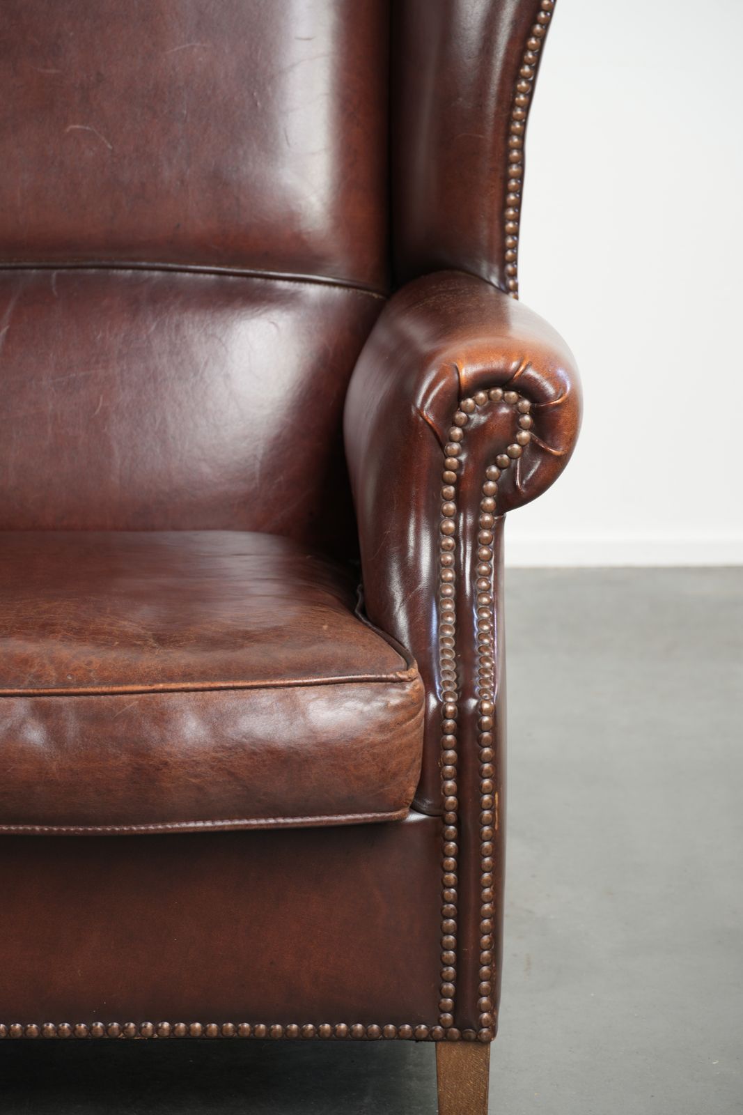 photo for sale Elegante Vintage Schapenvacht Vleugelfauteuil Met Een Tijdloze Engelse Uitstraling, Afgewerkt Met Decoratieve Sierspijkers.
