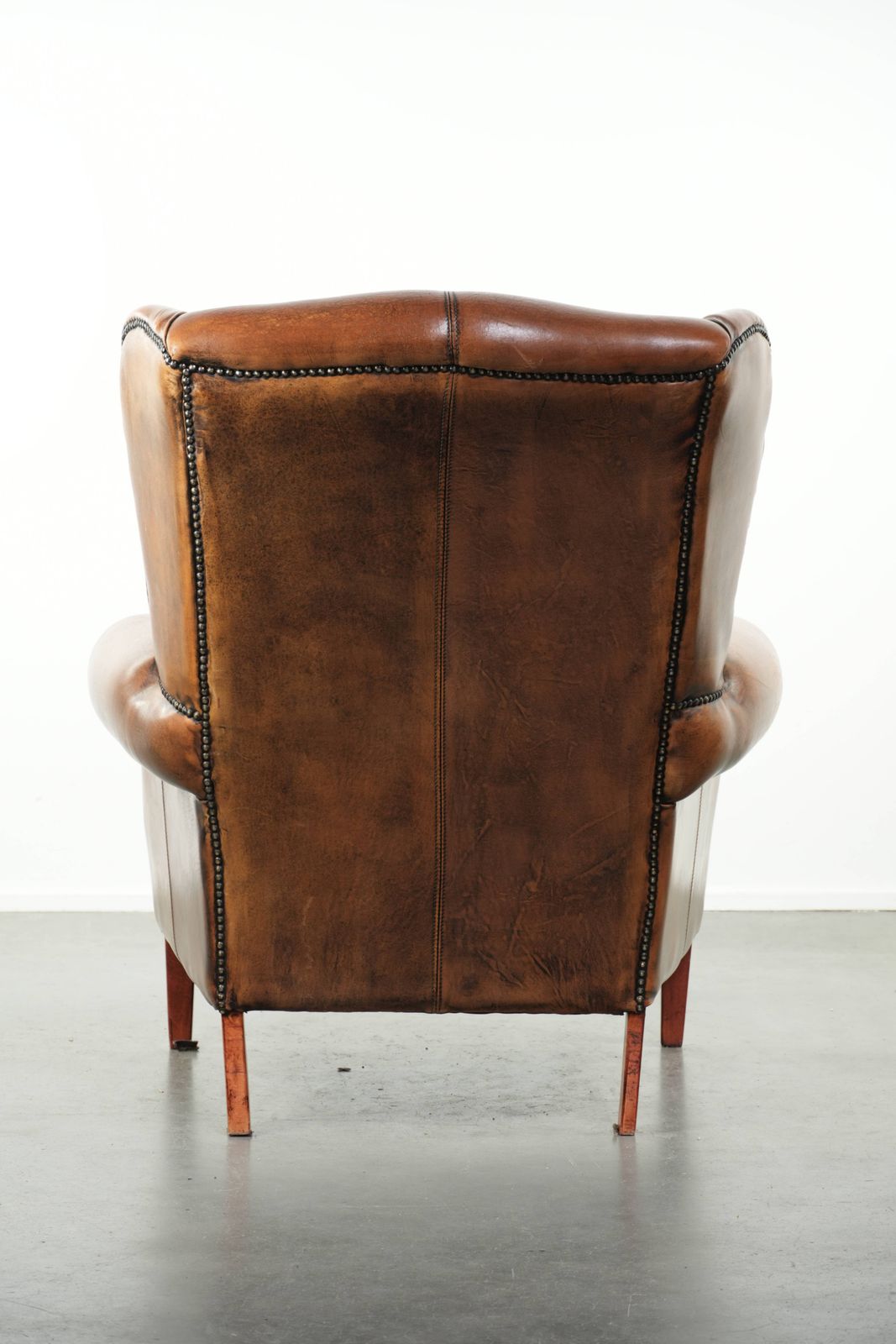 Comfortable Wing Armchair Made Of Sheepskin Finished With Decorative Studs And A Characterful English Style Appearance. photo Furniture