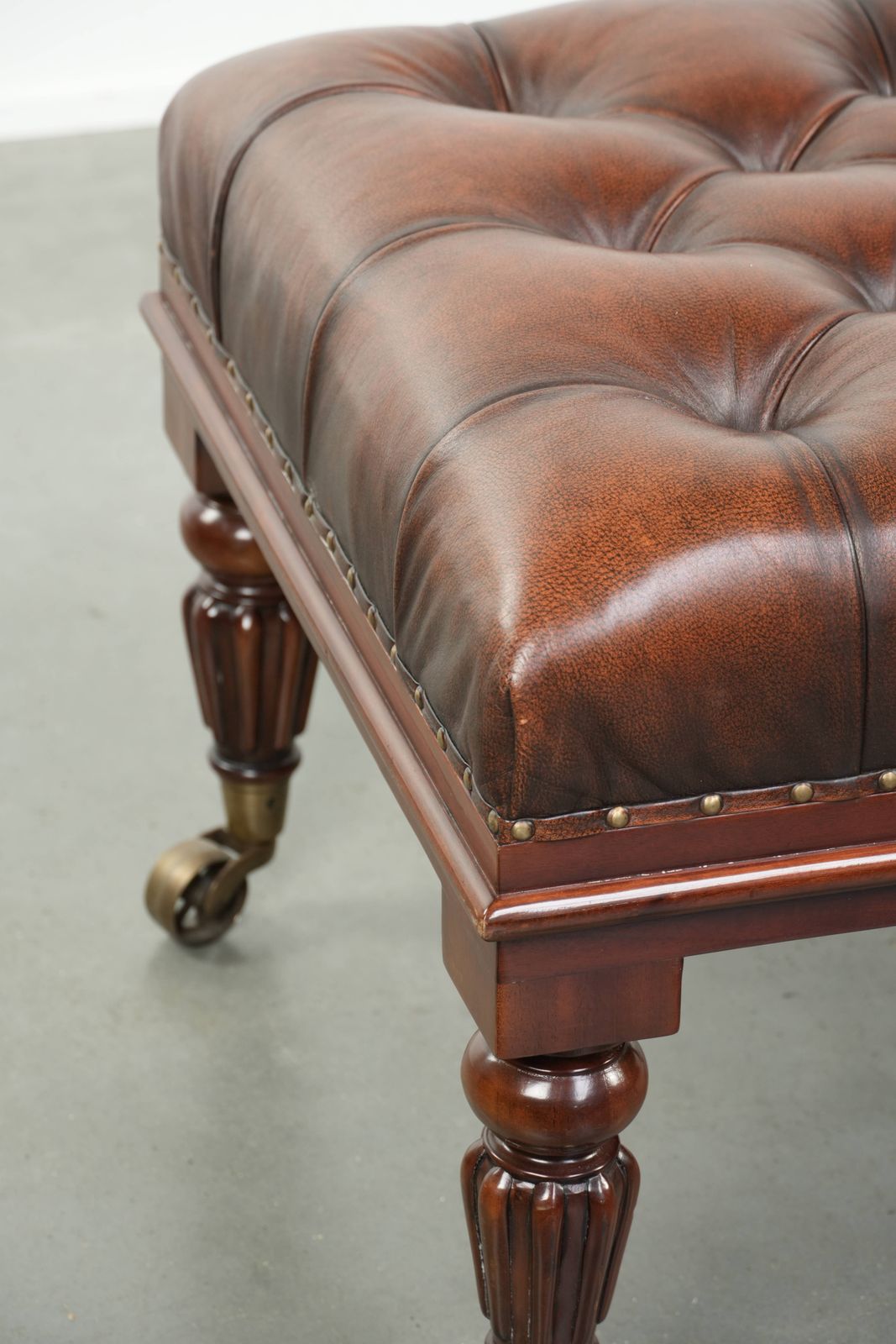 photo furniture Large Brown Cowhide Chesterfield Ottoman In English Style With Elegant Legs And Brass Casters