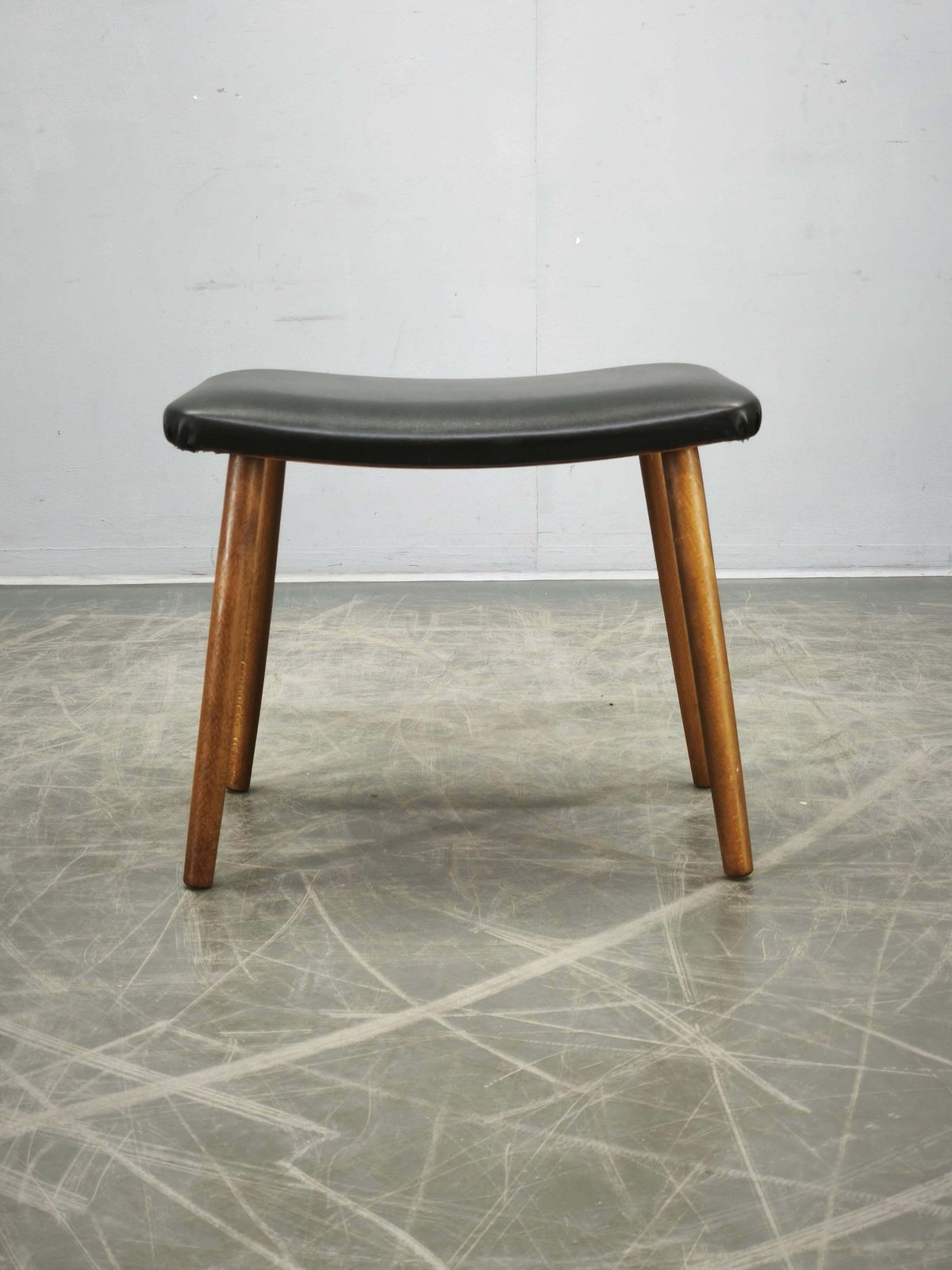 photo furniture Deens Modern beukenhouten voetenbank met zwarte vinyl bekleding, ca. jaren 1960.