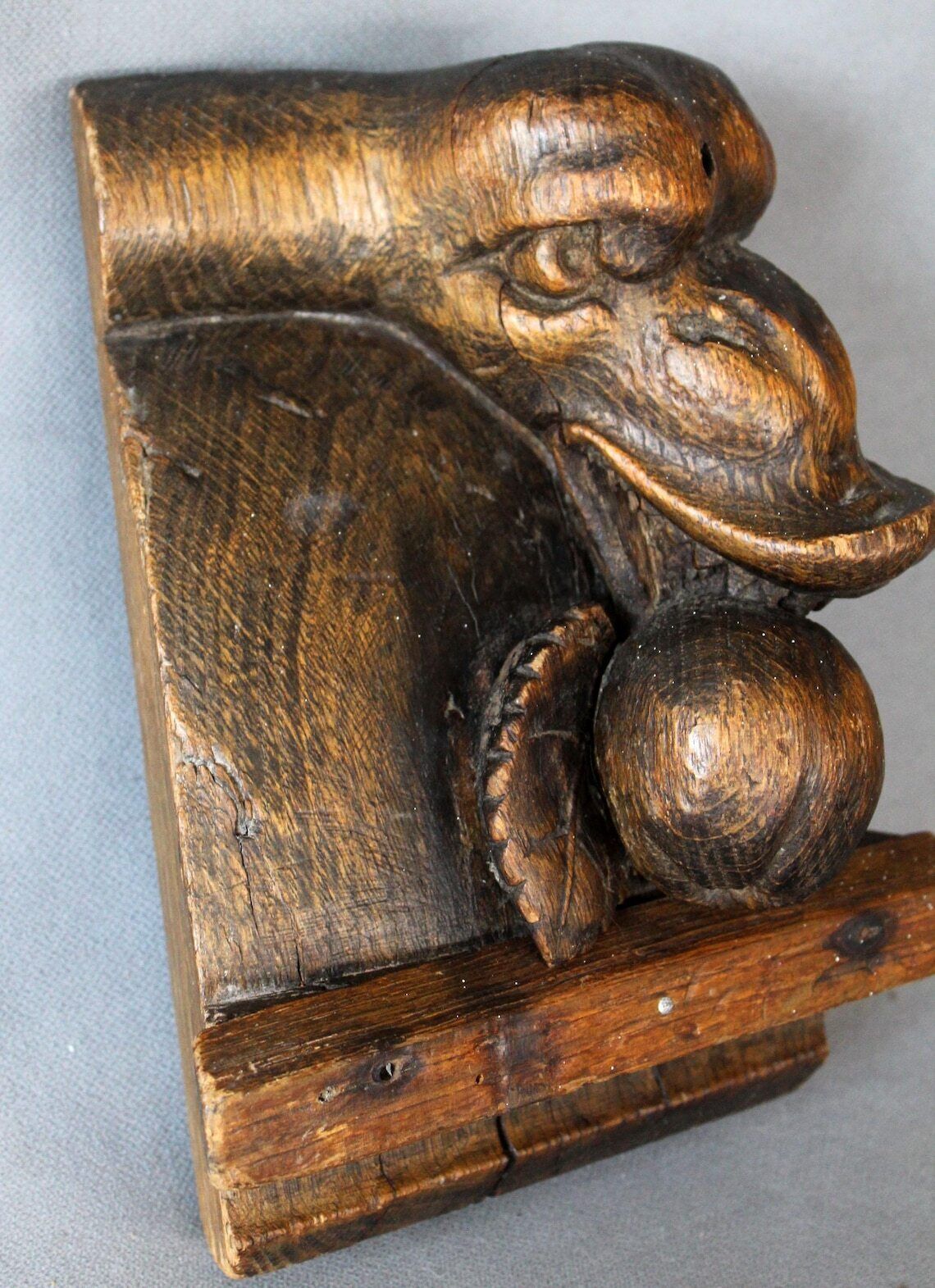 Groot antiek houten ornament in de vorm van een slangenkop met tanden die een appel of granaatappel eet, driedimensionaal, handgesneden, gotische architectuur photo buy