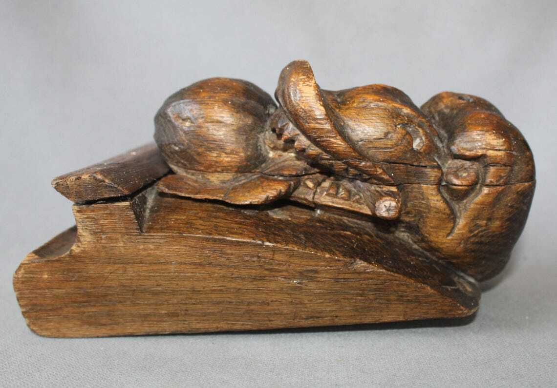 photo furniture Groot antiek houten ornament in de vorm van een slangenkop met tanden die een appel of granaatappel eet, driedimensionaal, handgesneden, gotische architectuur