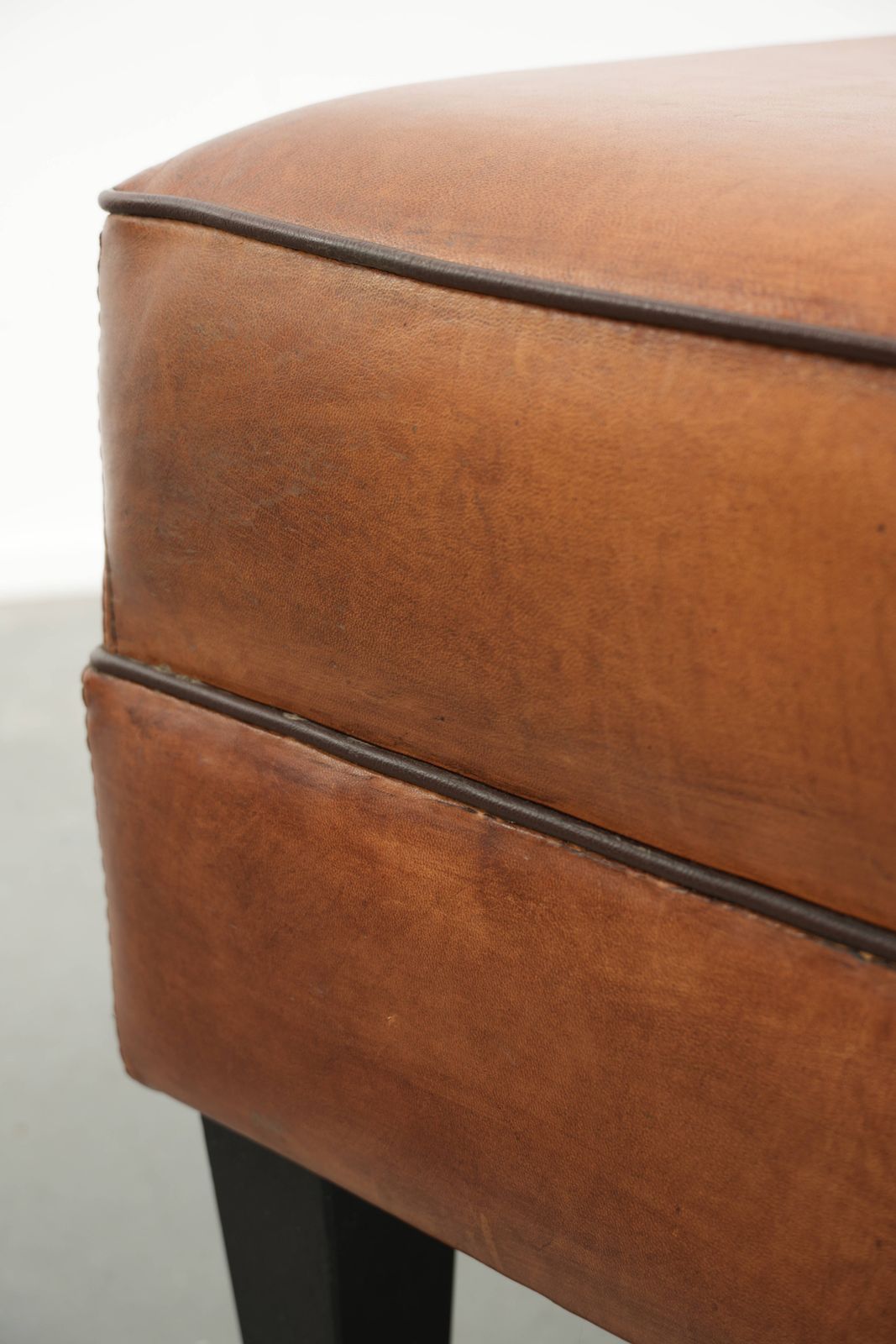 photo furniture Handy Sheepskin Ottoman With A Warm Color Scheme, Finished With Black Piping.