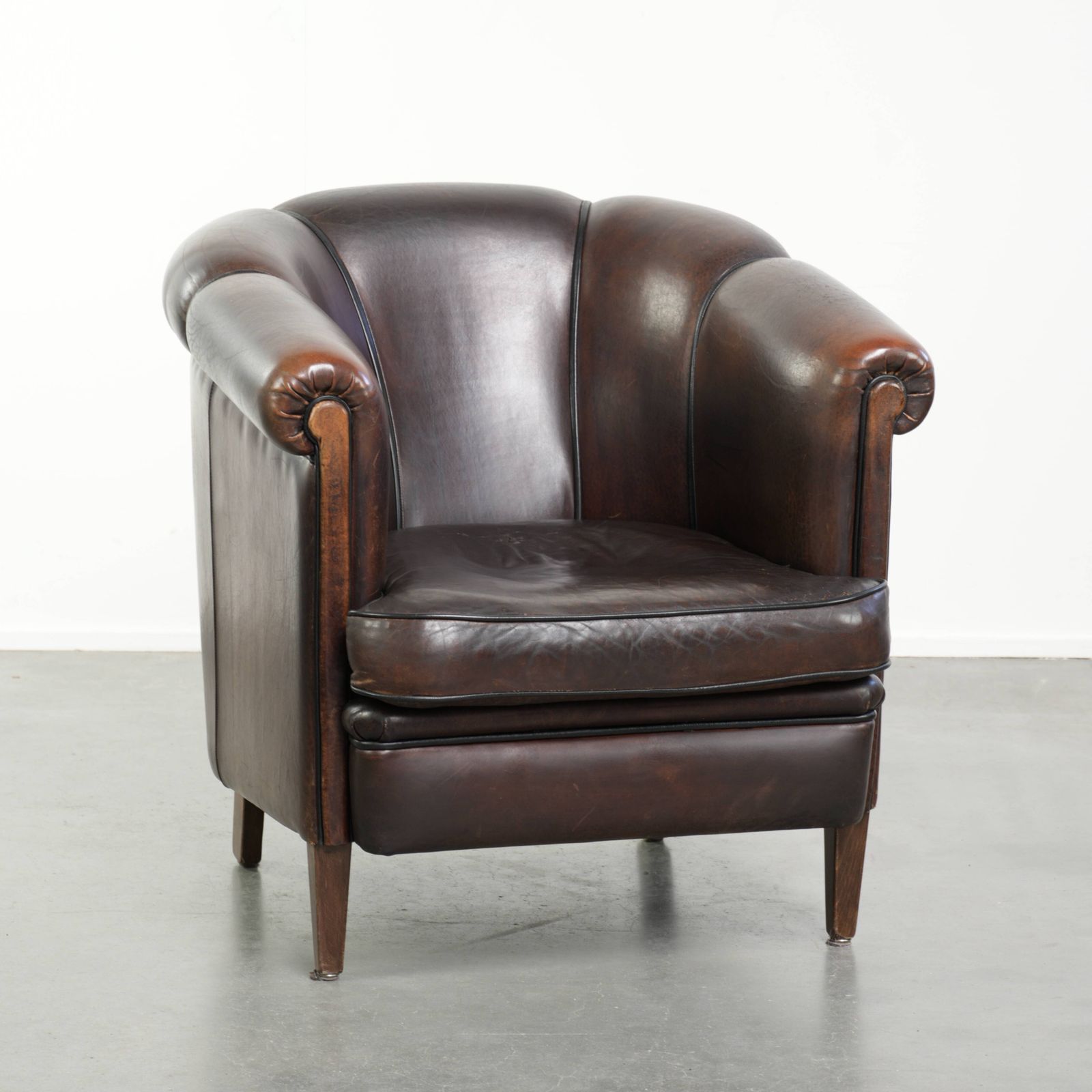 Donkere schapenleren club fauteuil met uniek ontwerp en aantrekkelijke patina in Engelse stijl.