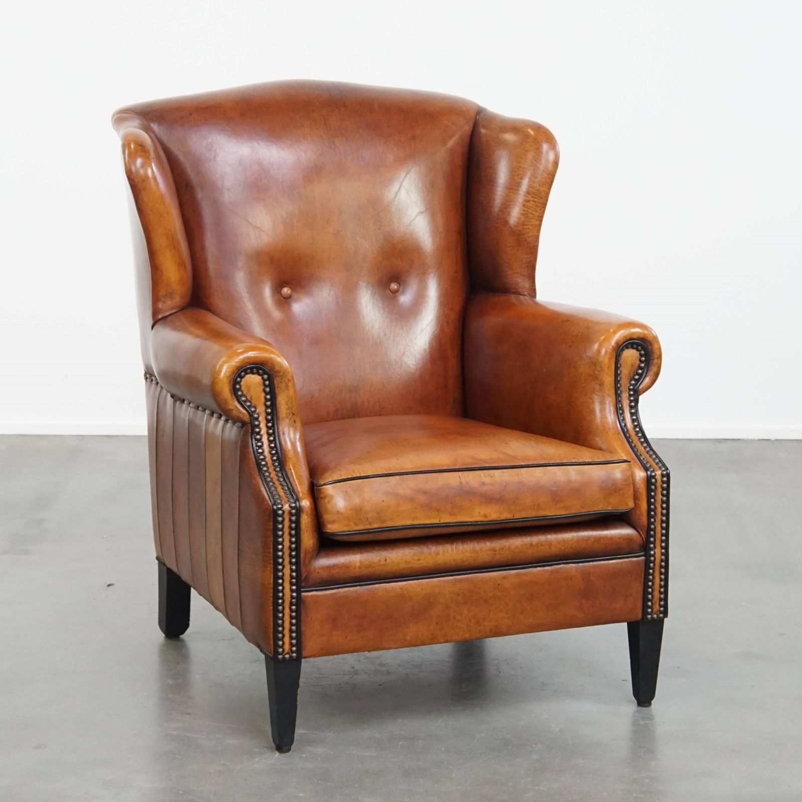 Comfortabele schapenvachten oorfauteuil met warme kleurstelling en afwerking met stiksels en zwart biesje.