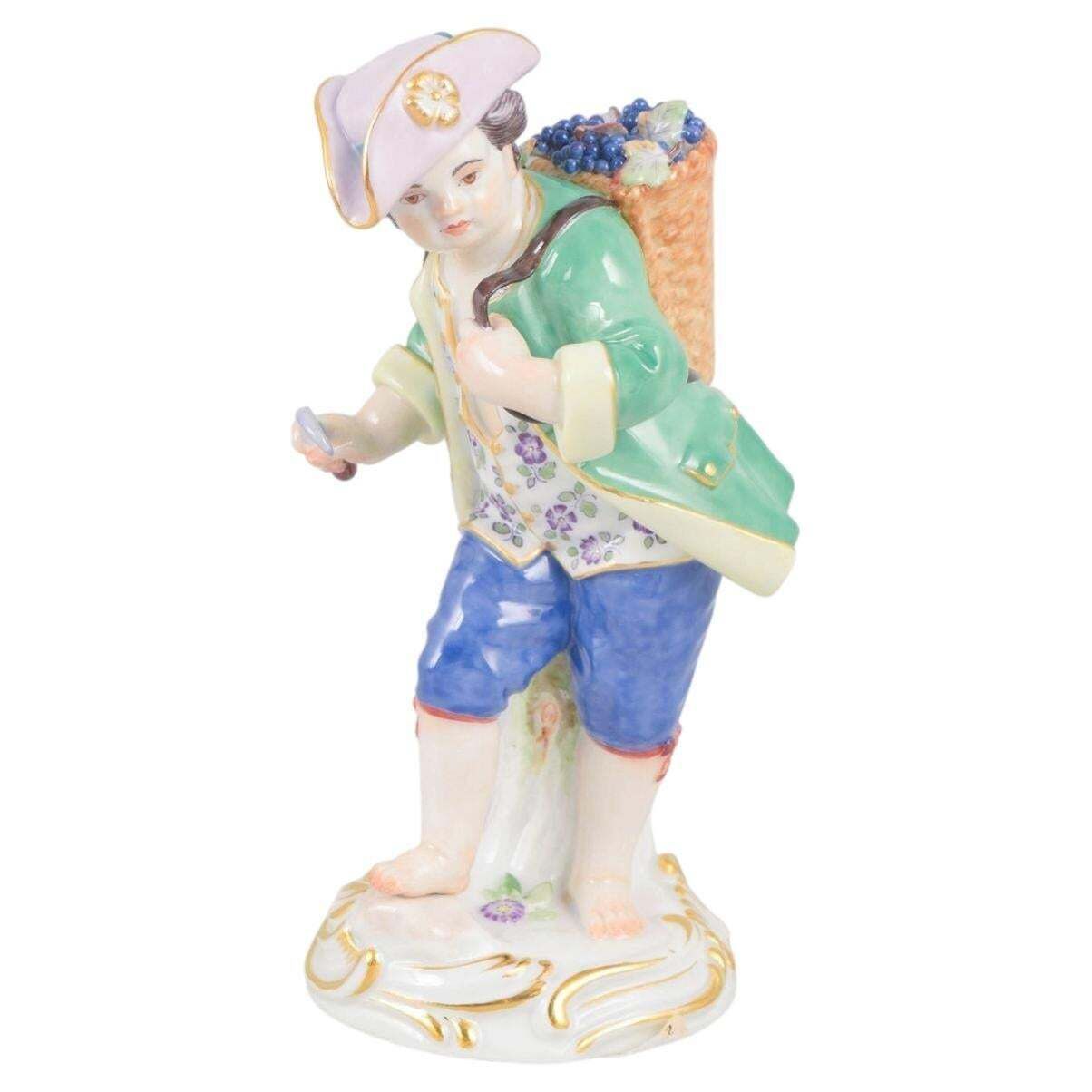 Meissen, Allemagne. Figurine en porcelaine d'un garçon au panier de raisins. Début du XXe siècle.