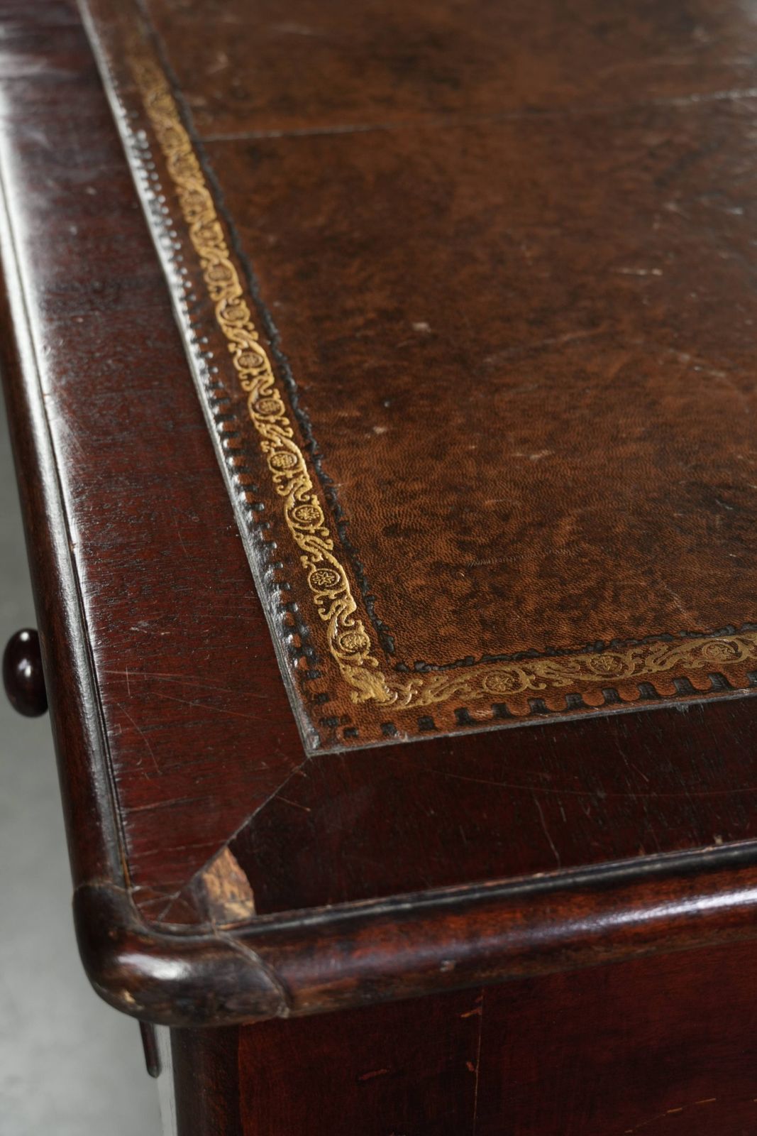 photo furniture Antiek Engels schrijfbureau uit de eind 19e eeuw met een warme houtkleur en een donkerbruin lederen blad met gouden accenten.
