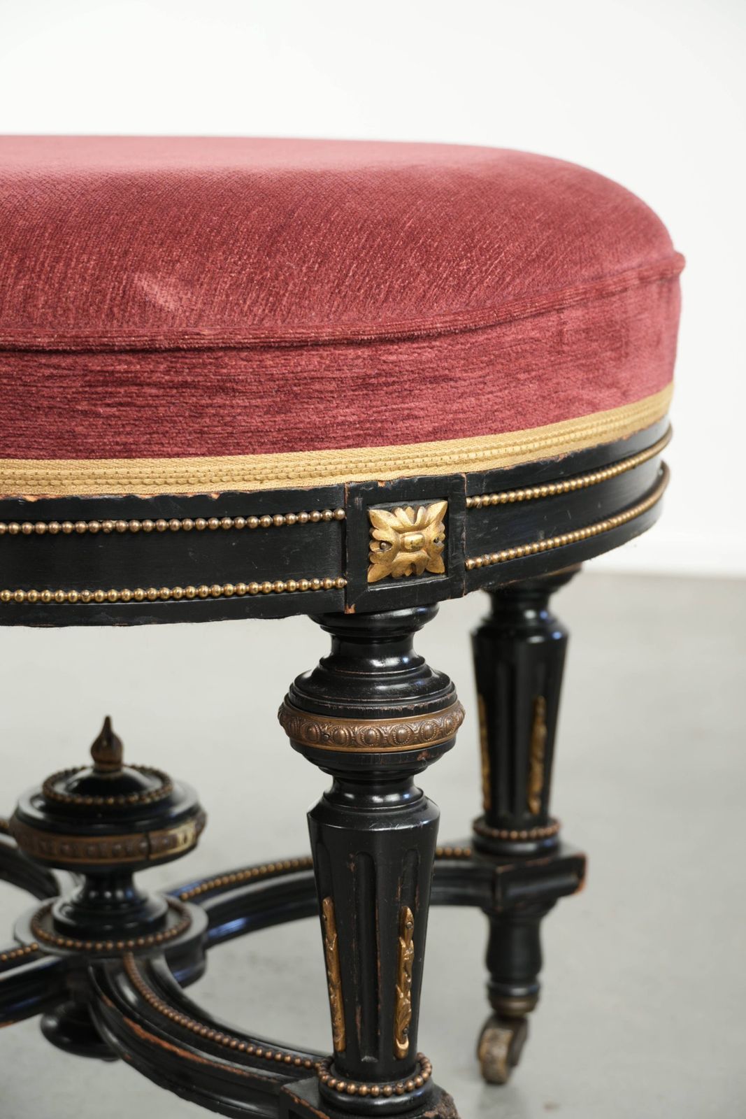 Antieke Engelse kruk met rode stoffen zitting en zwart houten onderstel met goudkleurige details photo vintage