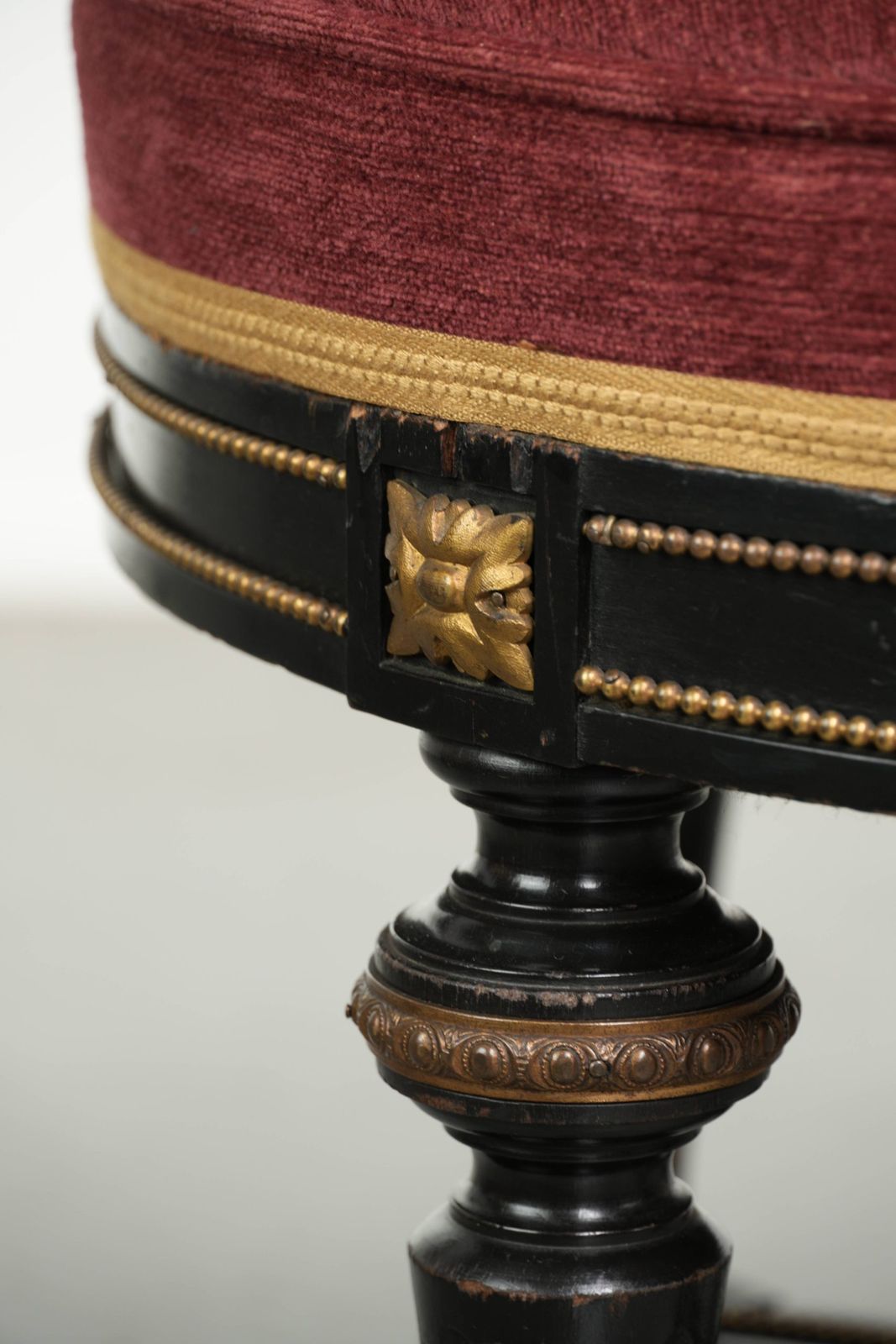 photo furniture Antieke Engelse kruk met rode stoffen zitting en zwart houten onderstel met goudkleurige details
