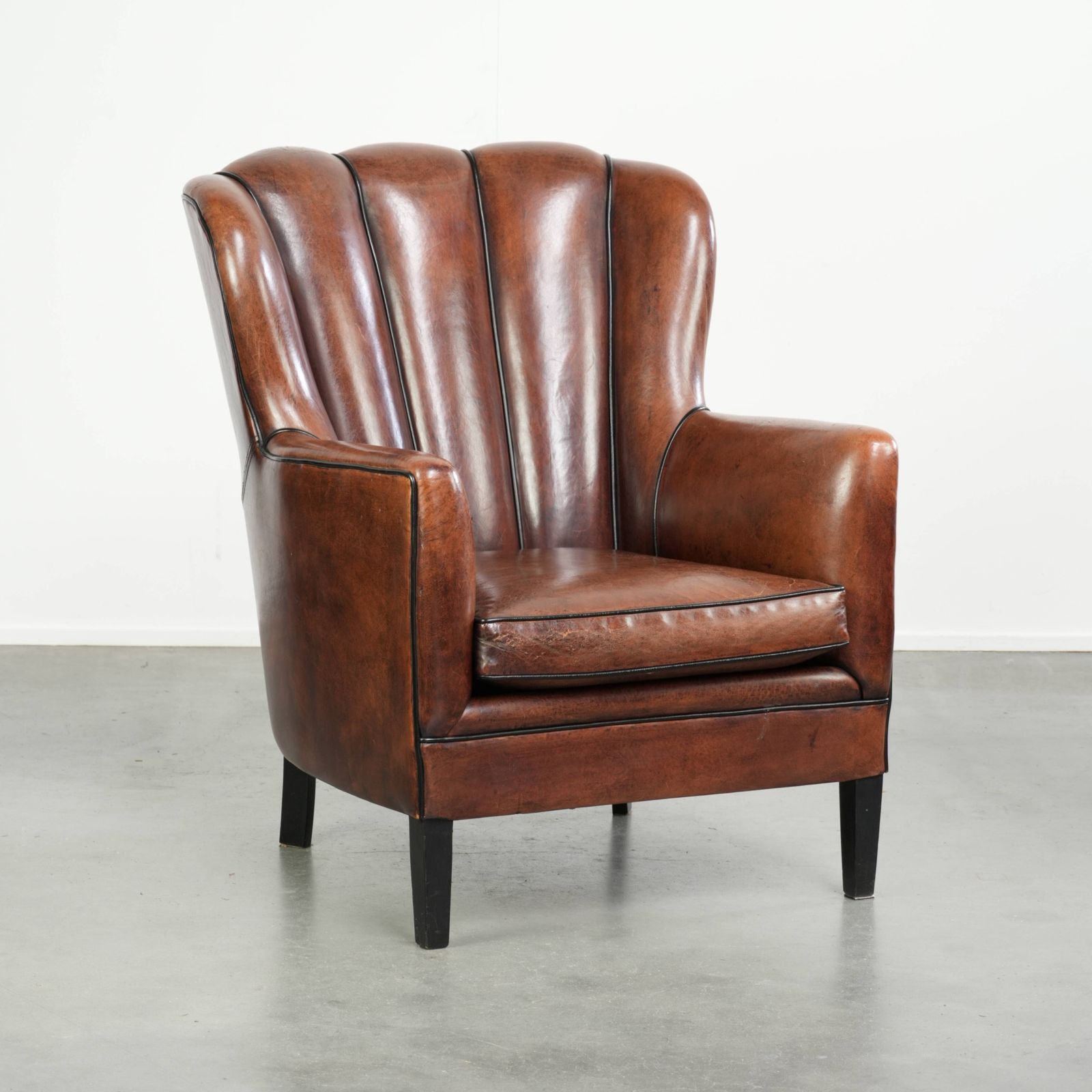 Unieke schapenleren fauteuil met warme, diepe kleuren, afgewerkt met zwarte biezen