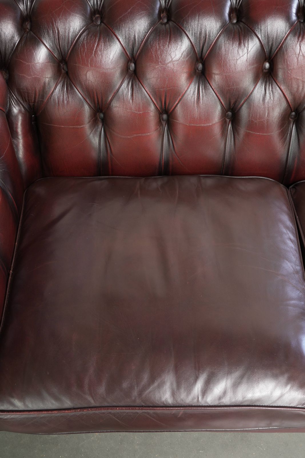 Tijdloze Chesterfield 2,5-zitsbank van koeienhuid in oxblood rood met mooie patina photo vinterior
