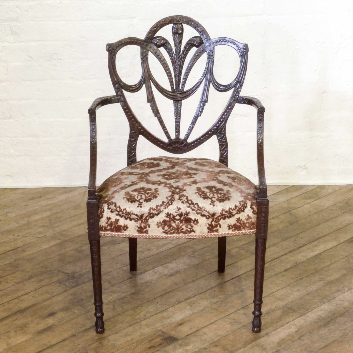 A Pair Of Edwardian Mahogany Armchairs In The Manner Of Hepplewhite. Profusely Carved With Foliage, Flowers, Ribbons And Swags. The Central Shield Bac photo vintage