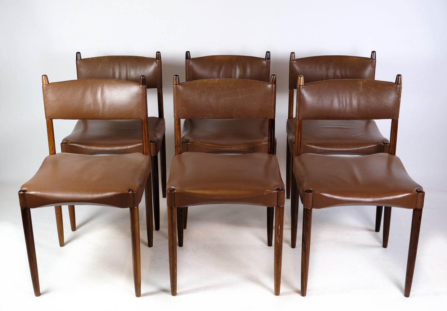 A Set Of 6 Chairs Of Danish Design Made In Solid Rosewood With Brown Leather From 1960s.